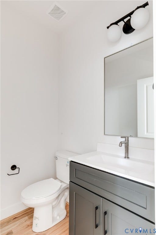 Dark grey vanity with a white countertop, integrated sink, metal hardware, a rectangular wall-mounted mirror, and a three-light fixture with globe shades