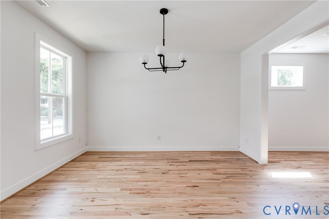 Wood-finish flooring, multi-pane window, and matte black chandelier with globe-style glass shades