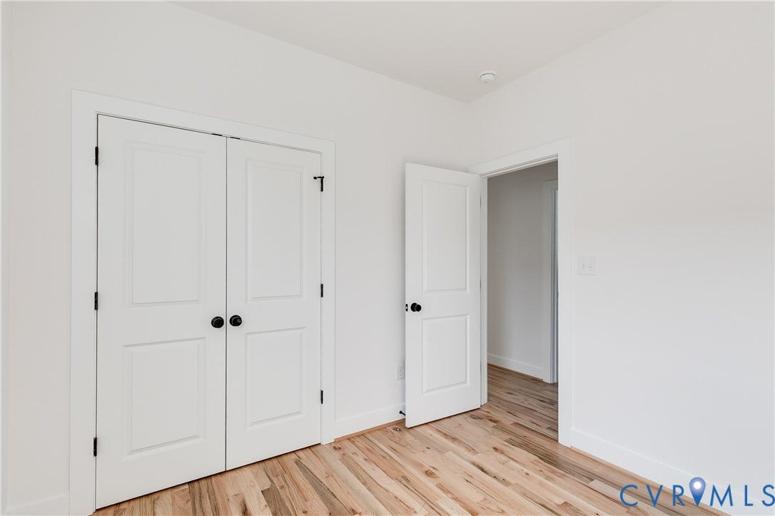 Room featuring wood-finish flooring, two-panel interior doors, and matte black hardware