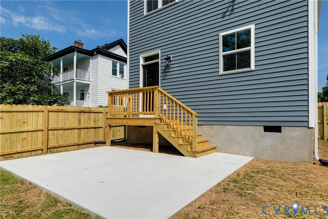 Exterior featuring horizontal siding, concrete patio, wooden deck with stairs, and perimeter wood fencing