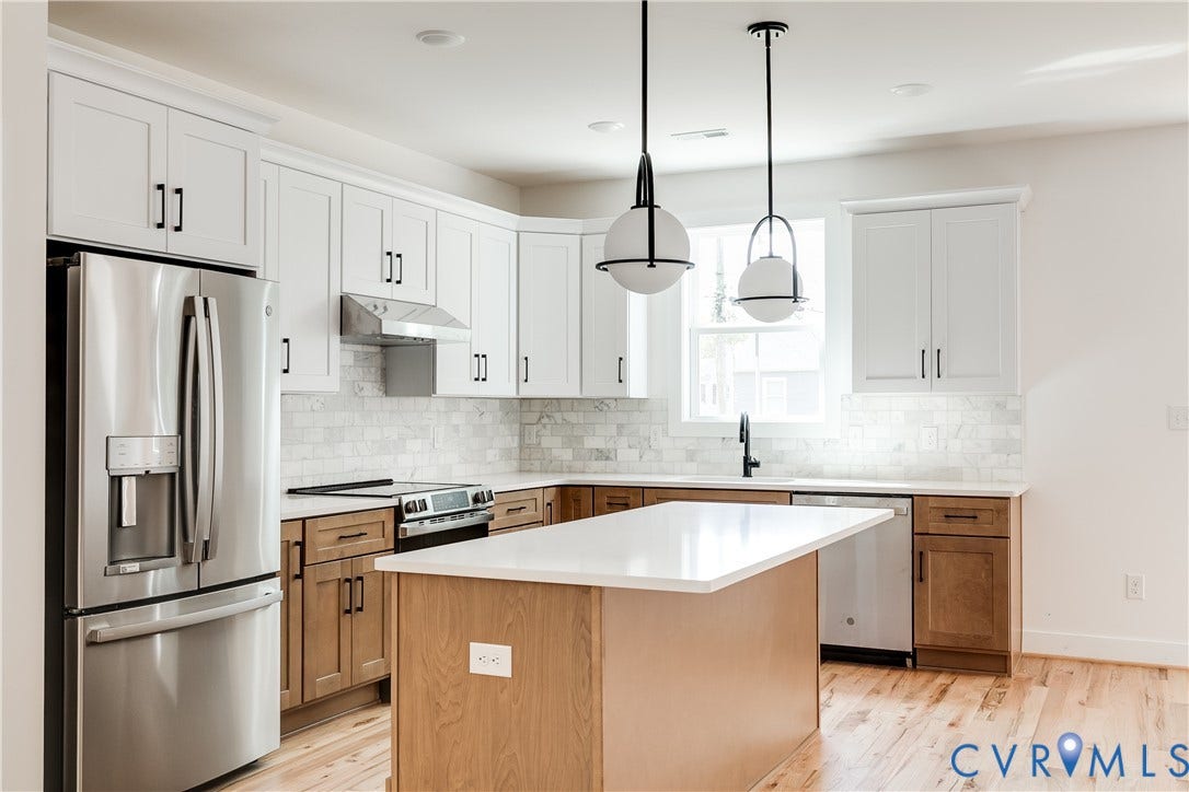Kitchen featuring two-tone cabinetry, central island with a solid-surface countertop, stainless steel appliances, stone-look tile backsplash, and wood-finish flooring