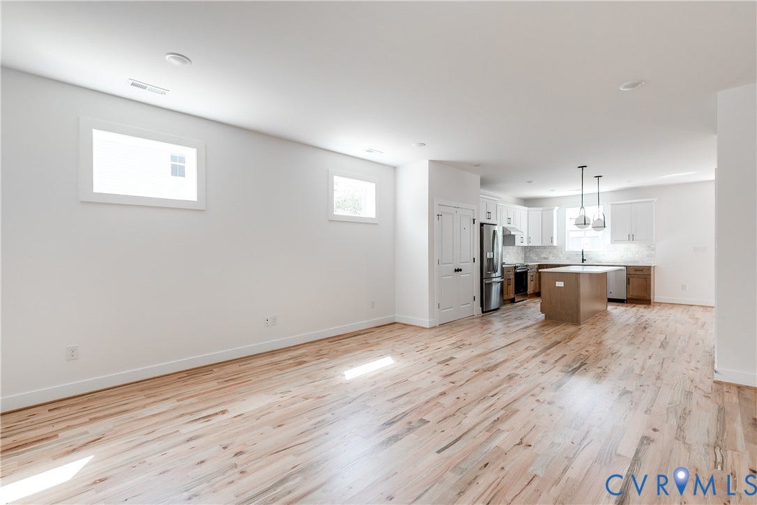 Open-concept area featuring wood-finish flooring, a kitchen island, recessed lighting, and white cabinetry