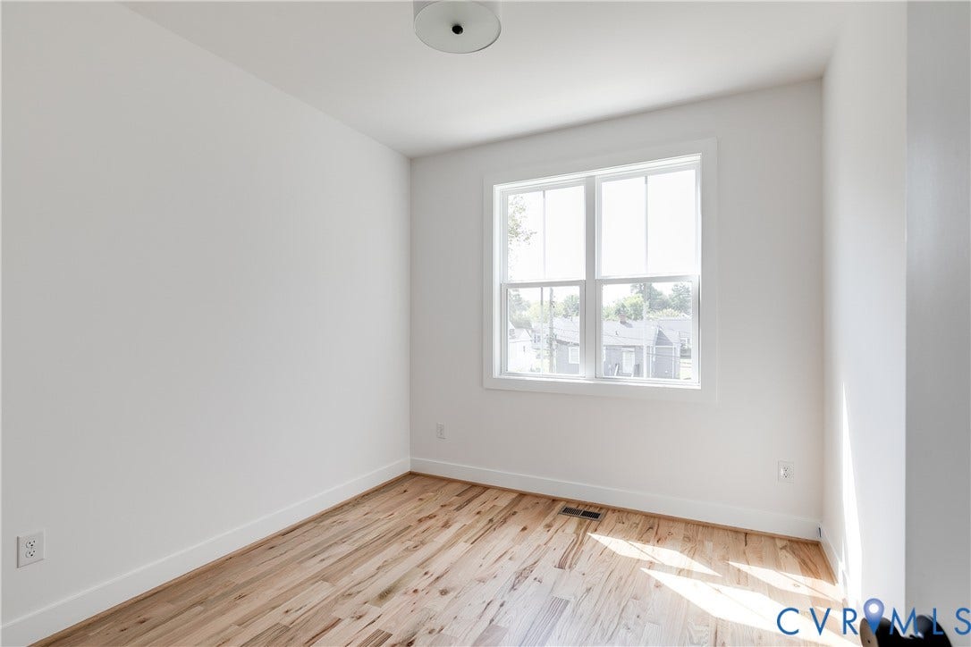 Room featuring light-toned wood-finish flooring, neutral wall paint, and a dual-pane window with white trim