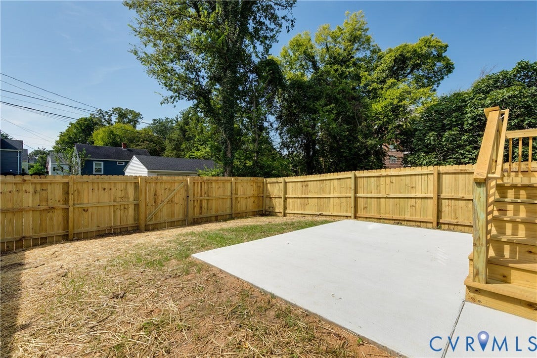 Backyard featuring a wood privacy fence, a concrete patio, and stairs with wooden railings