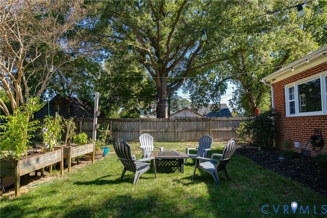 2108 Parkside Avenue, Henrico, VA 23228 Backyard space featuring a brick exterior facade, raised wooden garden beds, wood privacy fencing, and overhead string lighting