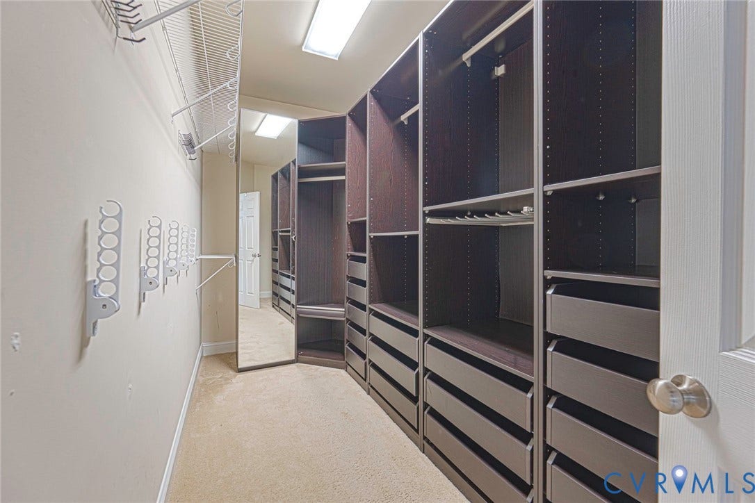9118 Colonnade Circle, Ashland, VA 23005 Custom walk-in closet featuring extensive dark-toned built-in cabinetry, integrated drawer storage, full-length mirror, and overhead lighting