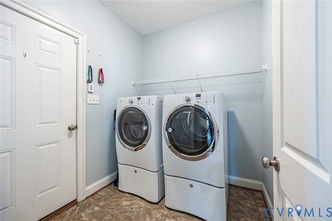 9118 Colonnade Circle, Ashland, VA 23005 Utility room featuring white front-loading appliances, patterned vinyl flooring, and wall-mounted wire shelving