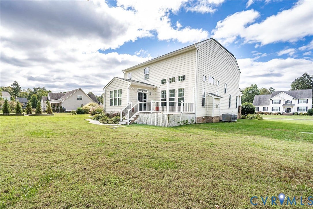 9118 Colonnade Circle, Ashland, VA 23005 Two-story residence featuring light-colored horizontal siding, a raised rear deck with balustrades, multiple windows, and a large level lawn