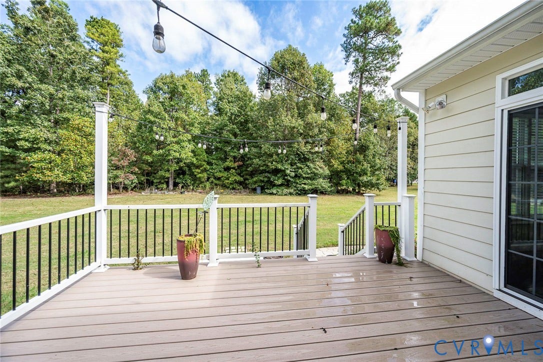 9118 Colonnade Circle, Ashland, VA 23005 Elevated rear deck featuring composite decking, white posts, and black metal balusters with integrated overhead string lighting