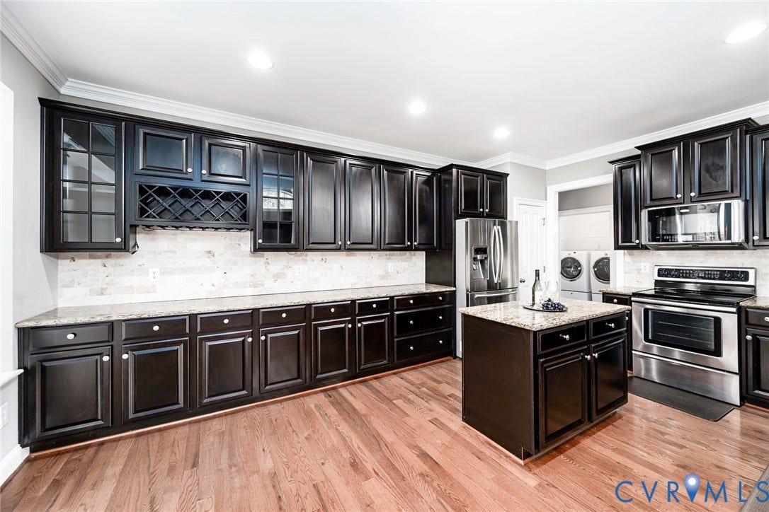 9118 Colonnade Circle, Ashland, VA 23005 Kitchen featuring dark cabinetry with built-in wine storage, stone countertops, stone tile backsplash, stainless steel appliances, and wood-finish flooring