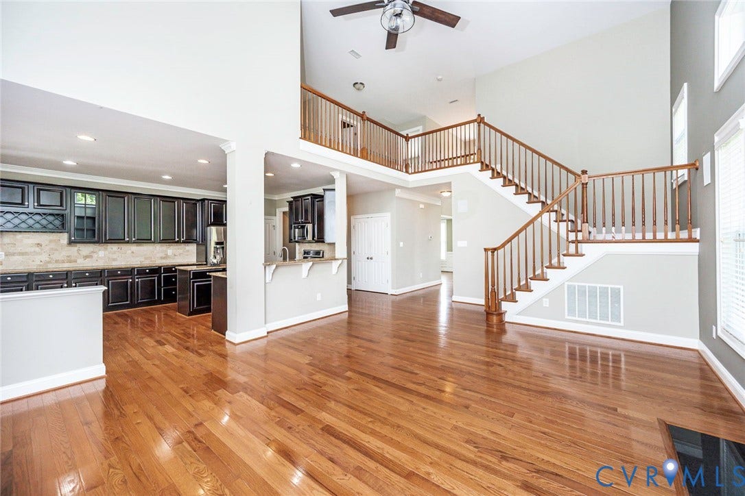 9118 Colonnade Circle, Ashland, VA 23005 Open-concept interior featuring vaulted ceilings, wood-finish flooring, dark-toned built-in cabinetry, and a staircase with a wooden balustrade