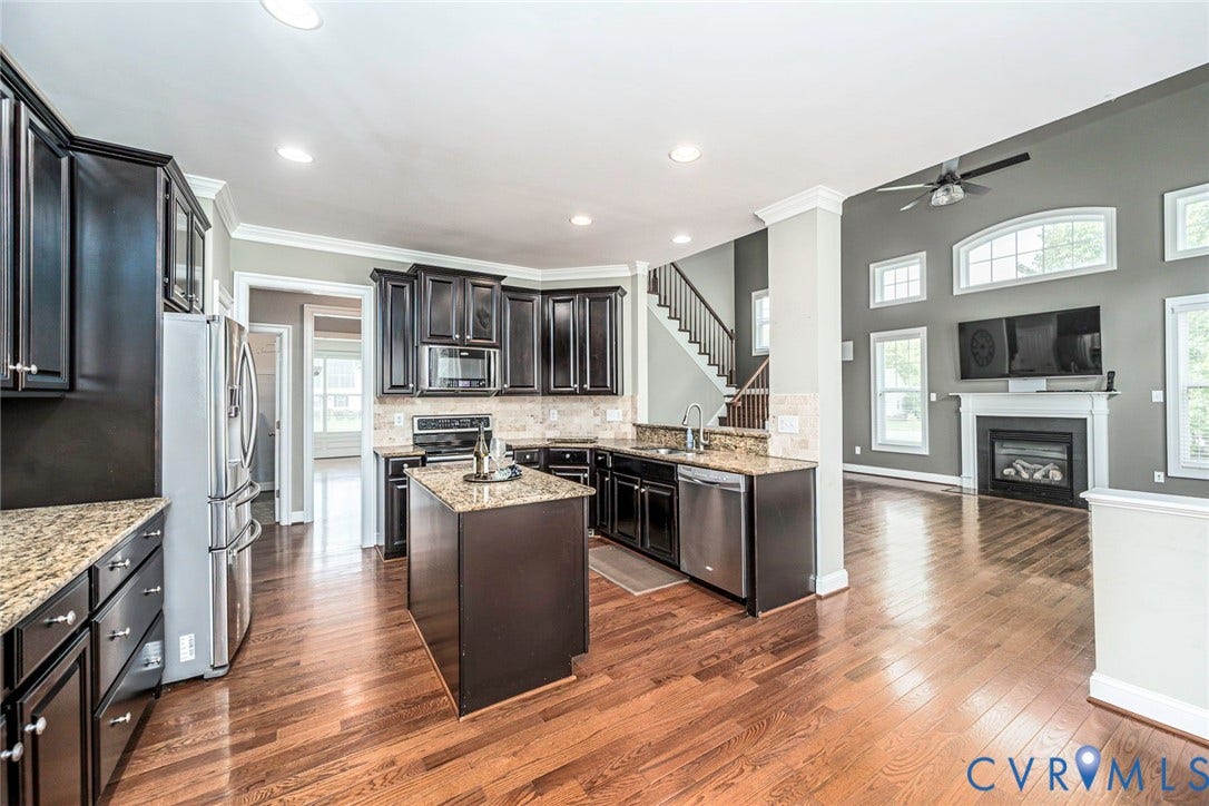 9118 Colonnade Circle, Ashland, VA 23005 Kitchen featuring dark cabinetry, stone countertops, stainless steel appliances, wood-finish flooring, and a fireplace with a decorative mantel