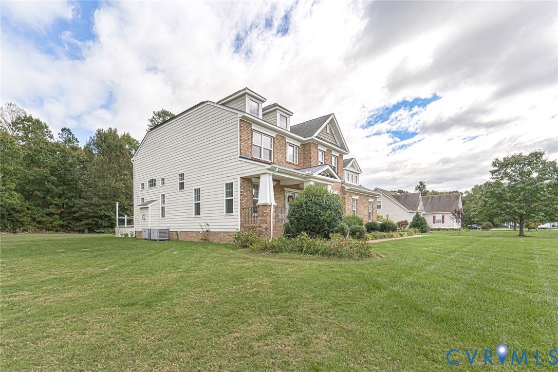 9118 Colonnade Circle, Ashland, VA 23005 Multi-story residence featuring brick and siding exterior, front-facing dormer windows, covered porch with tapered columns, and expansive lawn