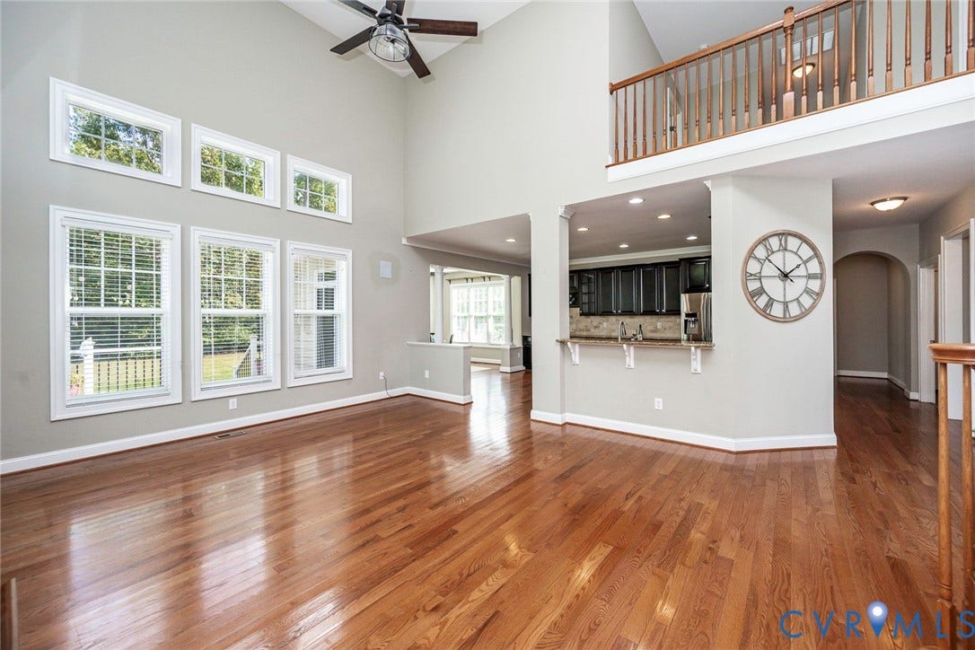 9118 Colonnade Circle, Ashland, VA 23005 Vaulted ceilings featuring a ceiling fan, wood-finish flooring, two-story windows, and a mezzanine with a wooden railing overlooking the main floor