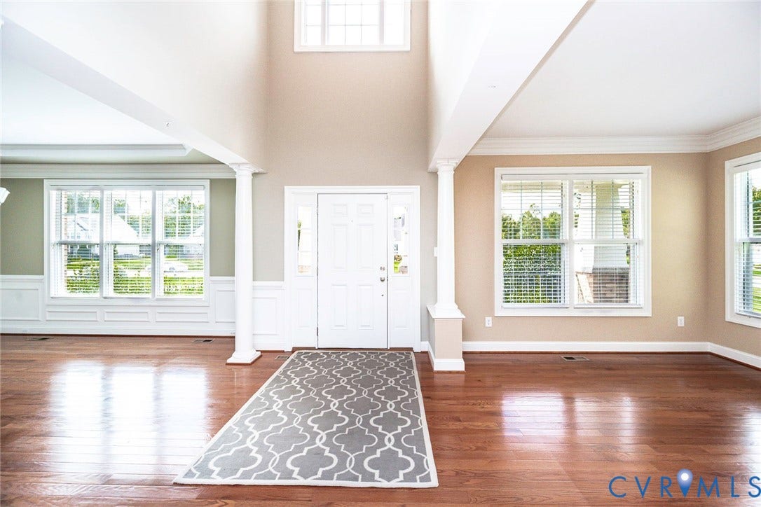 9118 Colonnade Circle, Ashland, VA 23005 Entryway featuring high ceilings, wood-finish flooring, white architectural columns, expansive windows, and crisp crown molding