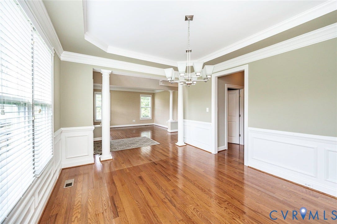 9118 Colonnade Circle, Ashland, VA 23005 Wood-finish flooring, white wainscoting, decorative columns, tray ceiling, and multi-light chandelier