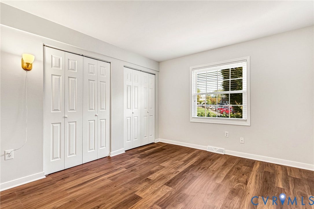 4 Millstone Road, The Hamlet, Henrico, VA 23228 Room featuring wood-finish flooring, dual sets of white paneled closet doors, a wall-mounted light fixture, and a window with horizontal blinds