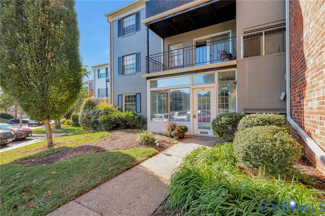 4 Millstone Road, The Hamlet, Henrico, VA 23228 Multi-story exterior featuring painted brick siding, second-level balcony with metal railing, ground-level glass-paneled entry, and multi-pane windows with shutters