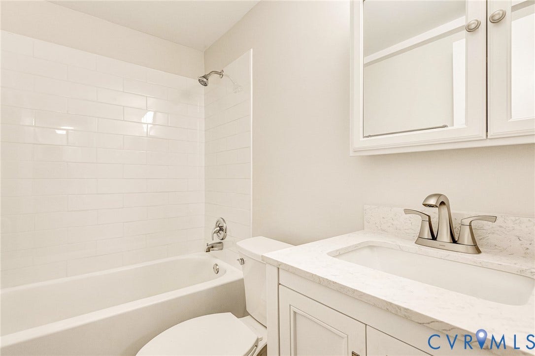 4 Millstone Road, The Hamlet, Henrico, VA 23228 Bathroom featuring a vanity with a stone-finish countertop, undermount sink, brushed nickel faucet, wall-mounted medicine cabinet, and a bathtub with white subway tile surround
