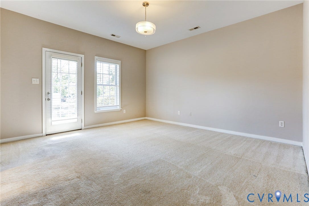 Neutral wall finishes, wall-to-wall carpeting, glass-paned exterior door, and single-light overhead pendant fixture