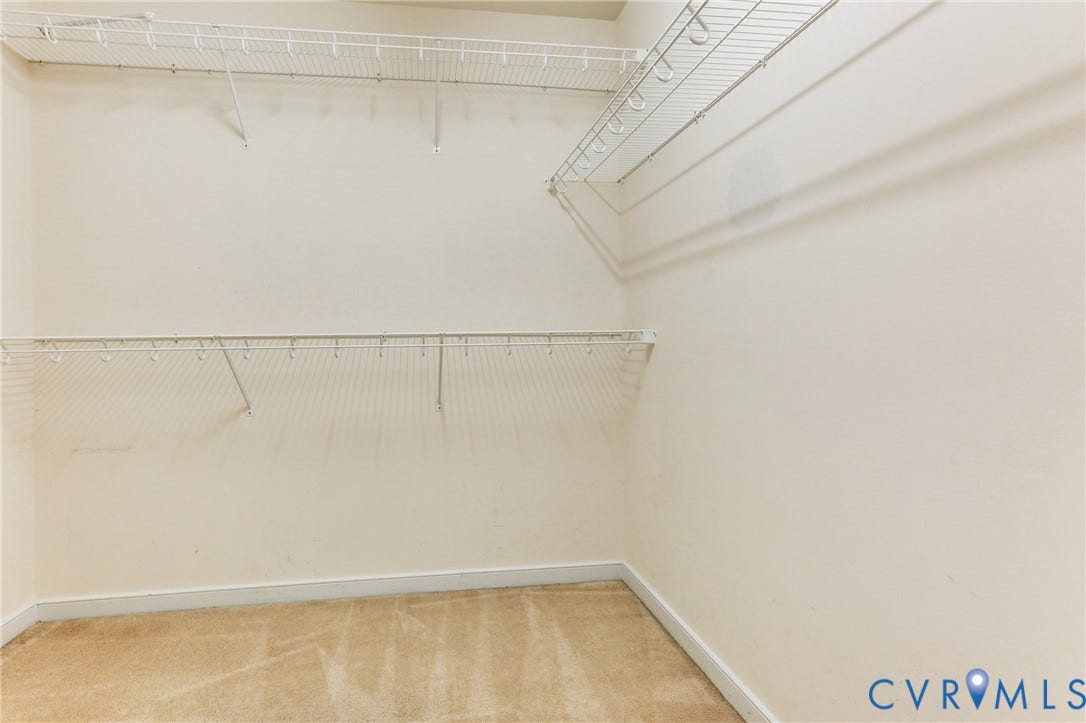 Walk-in storage space featuring dual-tier white wire shelving and wall-to-wall carpeting
