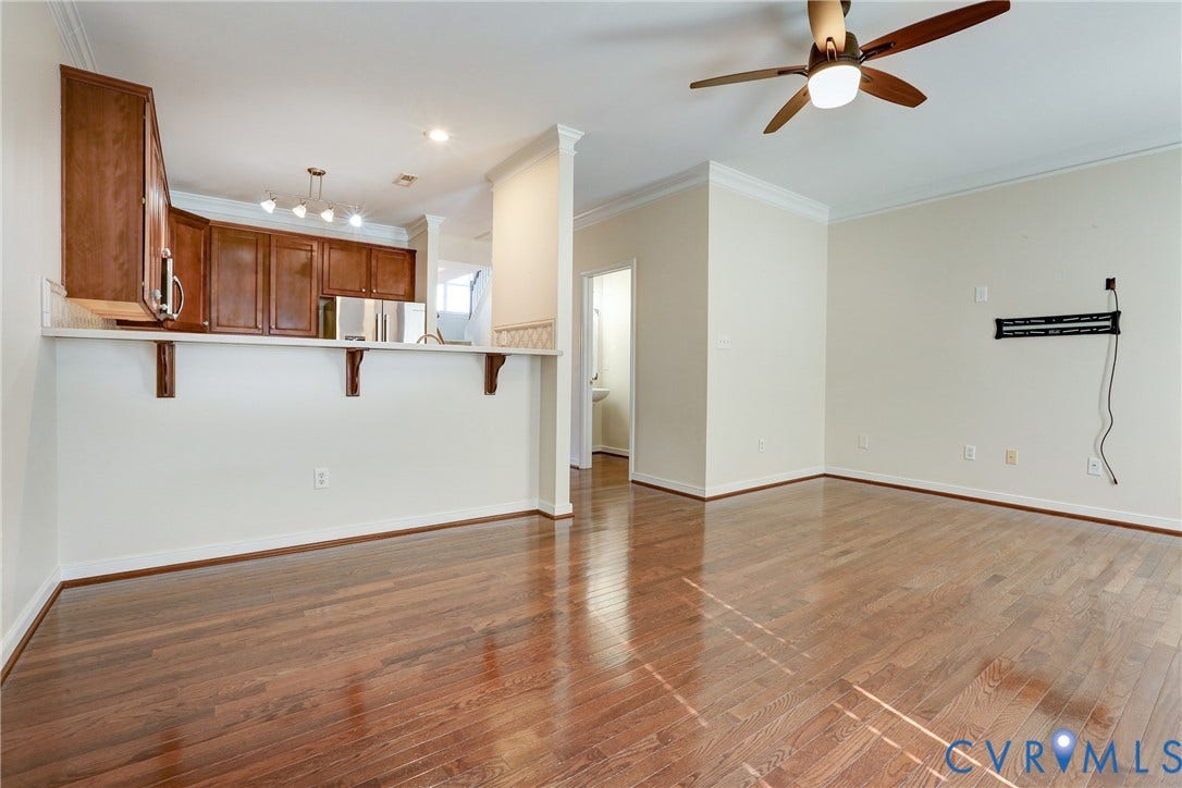 Wood-finish flooring, kitchen cabinetry with breakfast bar, and ceiling-mounted light fixture with fan