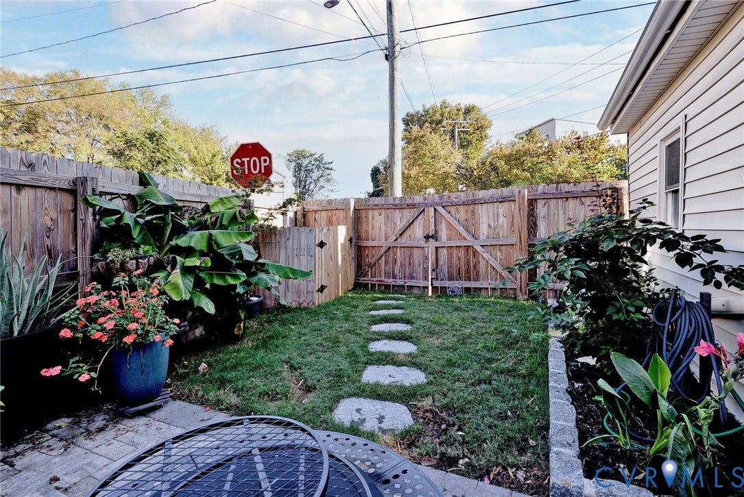 730 N 23RD Street, Union Hill, Richmond, VA 23223 Enclosed backyard featuring wood privacy fencing, a double-gate entry, natural stone paver pathway, and a stone-bordered garden bed.