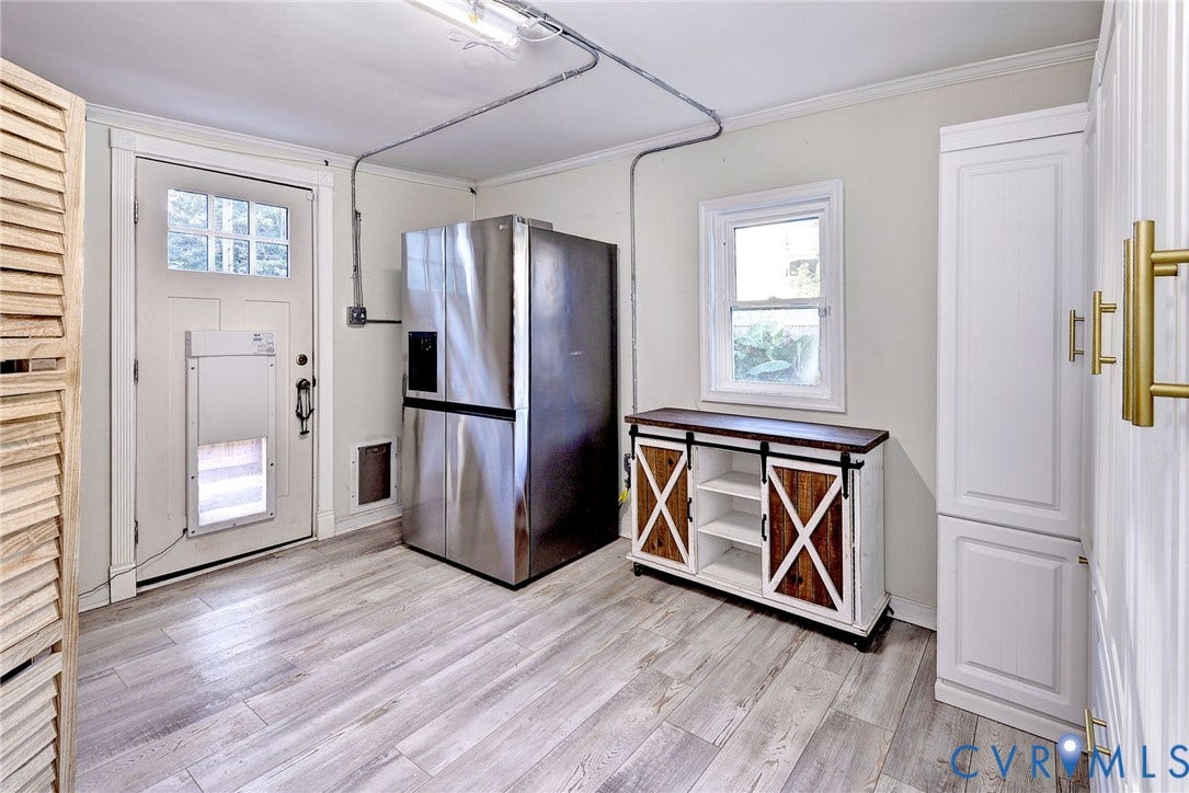 730 N 23RD Street, Union Hill, Richmond, VA 23223 Utility space featuring built-in cabinetry with lots of storage, stainless steel refrigerator, and pet door to fenced back yard.