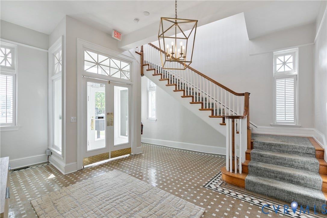 2800 Patterson Avenue, Richmond, VA 23221 Foyer featuring patterned tile flooring, a geometric metal chandelier, double-door entrance with transom windows, and a staircase with a wooden handrail and carpeted steps