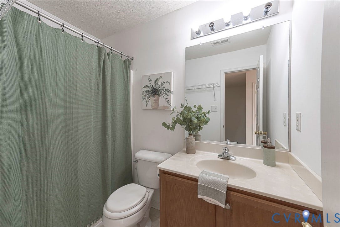 2408 Swartwout Avenue, Woodland Hills, Henrico, VA 23228 Full bathroom featuring a wood-finish vanity with a molded countertop, integrated basin, chrome faucet, and a wall-mounted light fixture above a large mirror