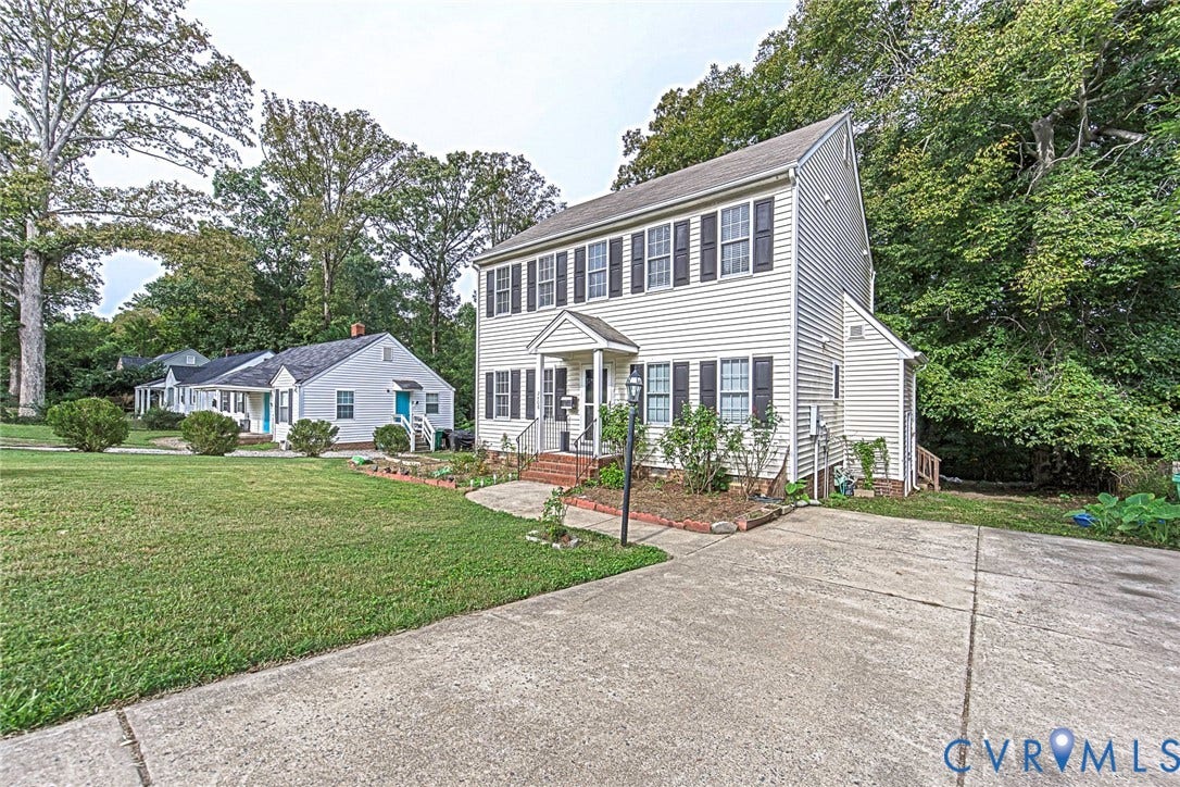 2408 Swartwout Avenue, Woodland Hills, Henrico, VA 23228 Two-story residence featuring light-colored siding, multi-pane windows with dark shutters, brick-accented front entryway, and a paved driveway