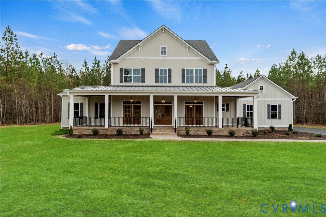 18128 Dogwood Trail Way, Rockville, VA 23146 Two-story farmhouse exterior featuring vertical board-and-batten siding, a metal-roofed wraparound porch, dark-finished window shutters, and stone-veneer skirting