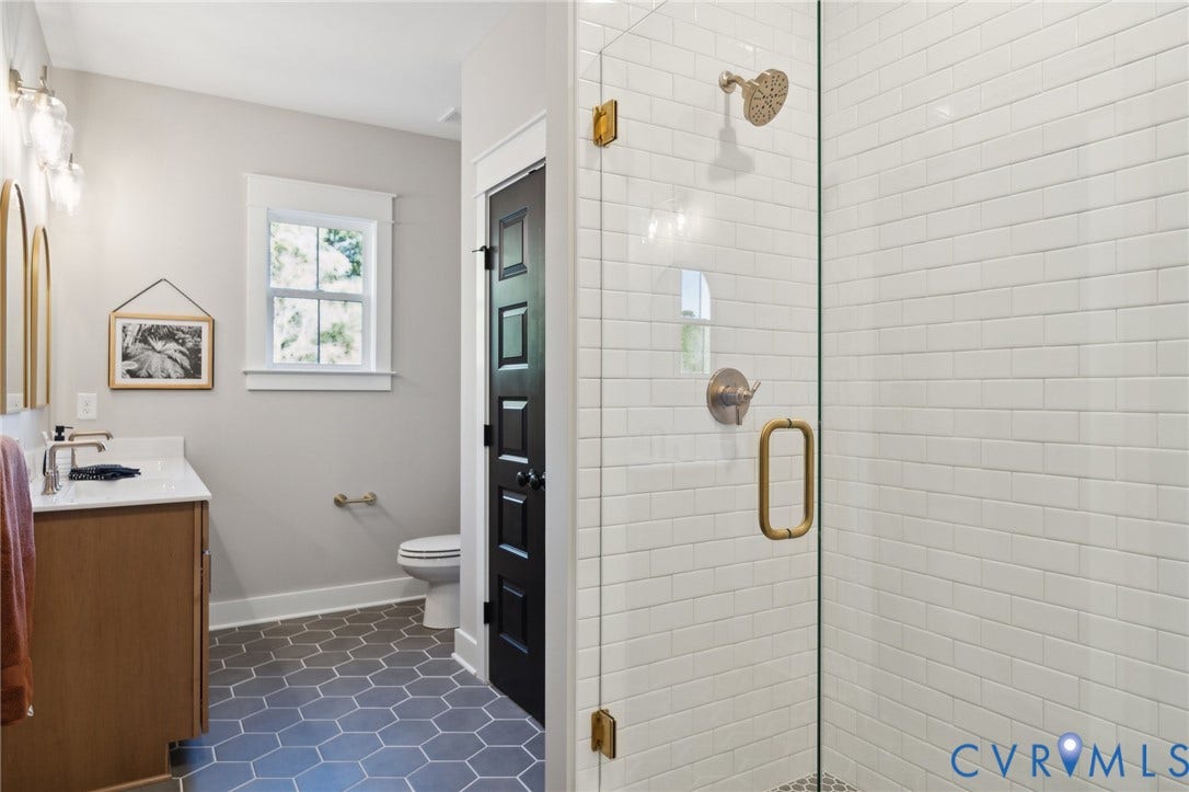 18128 Dogwood Trail Way, Rockville, VA 23146 Bathroom featuring a walk-in shower with white subway tile, glass enclosure, and metallic hardware, complemented by hexagon floor tile, a wood-finish vanity, and a white countertop