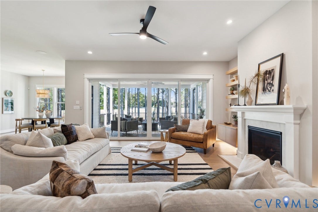 18128 Dogwood Trail Way, Rockville, VA 23146 Open-concept living space featuring wood-finish flooring, a masonry fireplace with a classic mantel, built-in recessed shelving, a modern ceiling fan, and oversized sliding glass doors