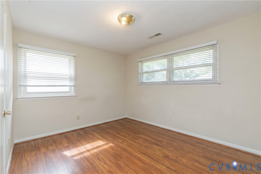 2108 Ridgemont Road, Richmond, VA 23224 Neutral interior featuring wood-finish flooring, two sets of double-pane windows with horizontal blinds, and a circular flush-mount ceiling light fixture