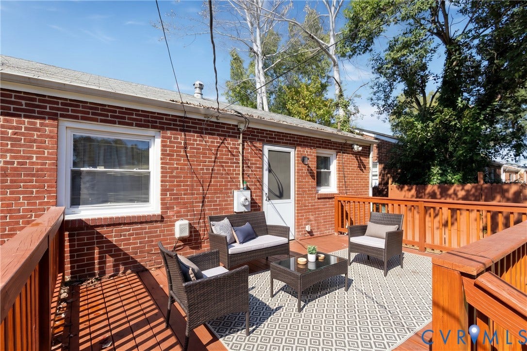 2108 Ridgemont Road, Richmond, VA 23224 Exterior red brick facade featuring a raised wood-finish deck with integrated railing and a partial wood fence