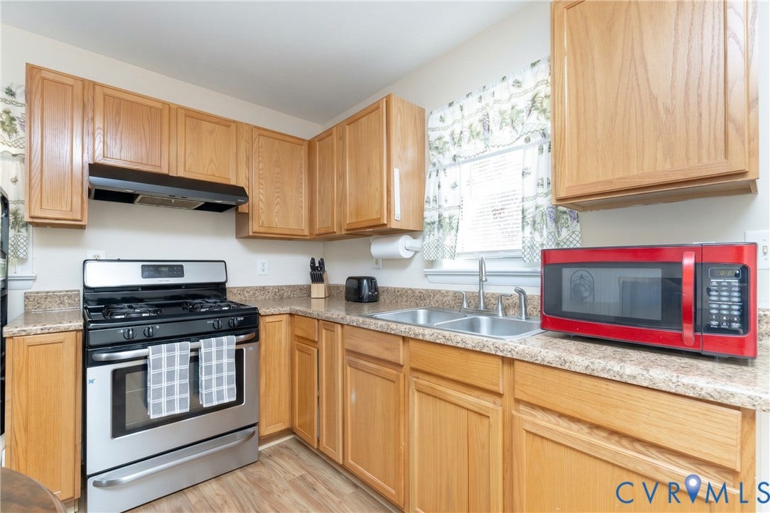 2108 Ridgemont Road, Richmond, VA 23224 Kitchen featuring wood cabinetry, laminate countertops, stainless steel gas range, and double-basin stainless steel sink