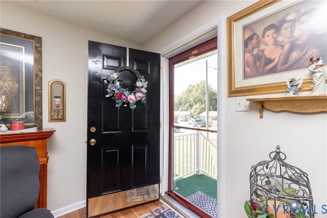 2108 Ridgemont Road, Richmond, VA 23224 Entryway featuring a black multi-panel door with a polished metal kickplate, glass-paneled storm door, and wood-finish flooring