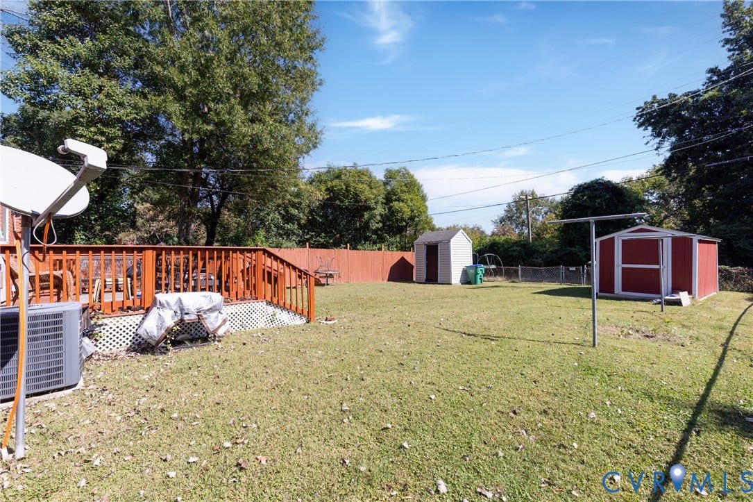 2108 Ridgemont Road, Richmond, VA 23224 Backyard featuring a raised wood deck, perimeter privacy fencing, and two storage structures