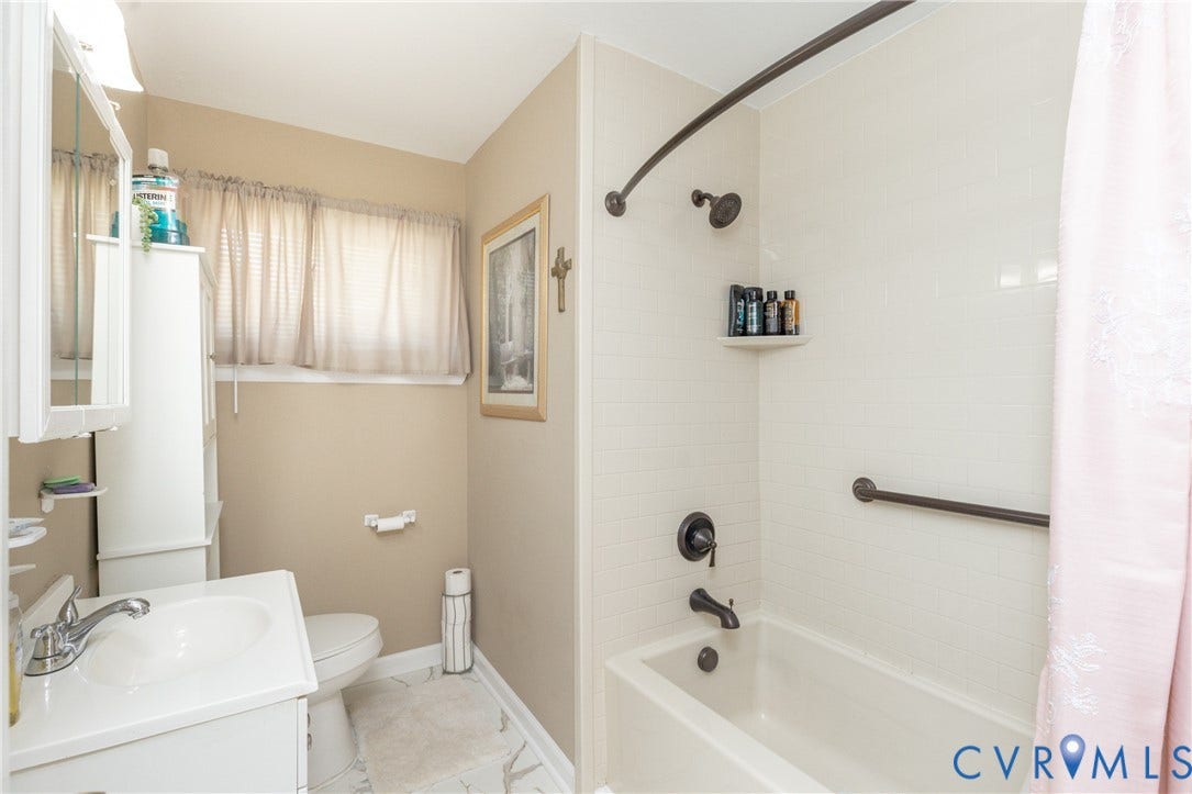 2108 Ridgemont Road, Richmond, VA 23224 Bathroom featuring a white vanity cabinet, ceramic tile tub surround, and bronze-finish shower fixtures with integrated safety rail