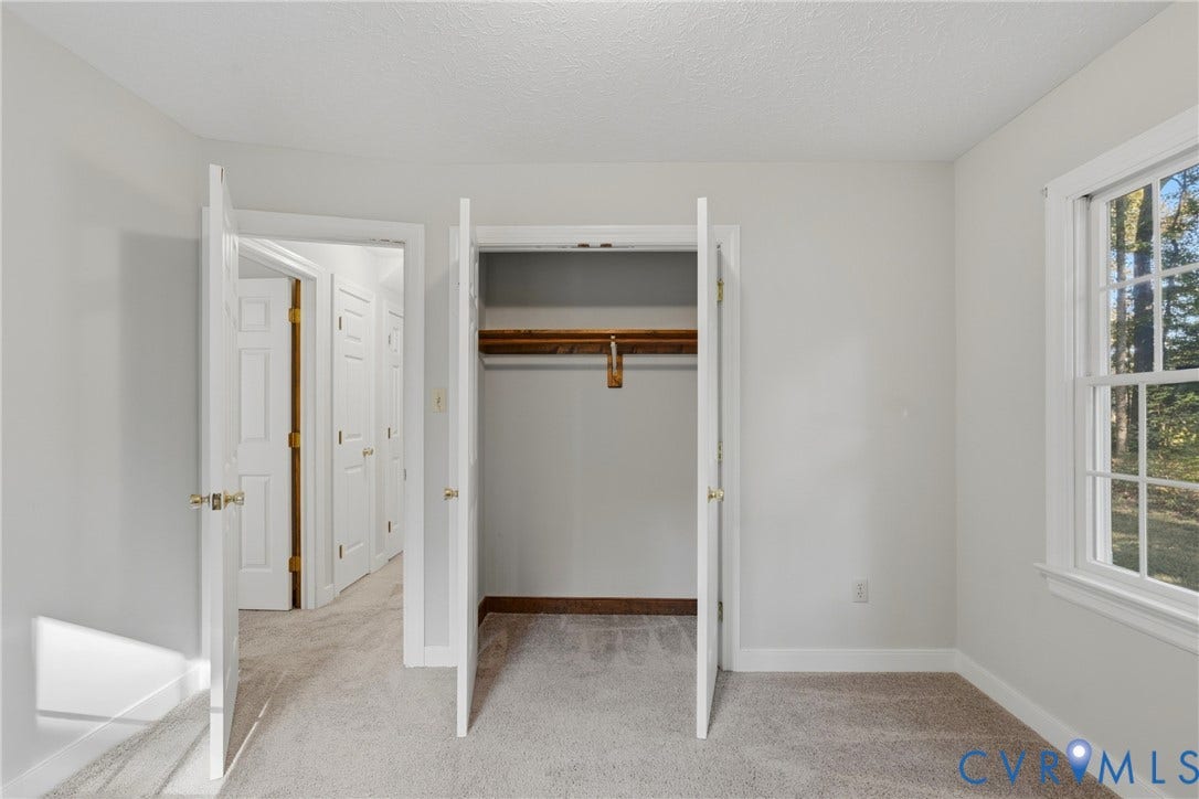 7270 Crossing Oaks Trail, Mechanicsville, VA 23111 Interior space featuring neutral-toned carpeting, a built-in reach-in closet with overhead shelving, multi-panel doors, and a double-hung window with muntin detailing