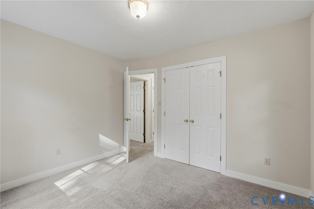 7270 Crossing Oaks Trail, Mechanicsville, VA 23111 Neutral-toned interior room featuring wall-to-wall carpeting, a double-door closet with six-panel doors, and a central overhead ceiling light fixture