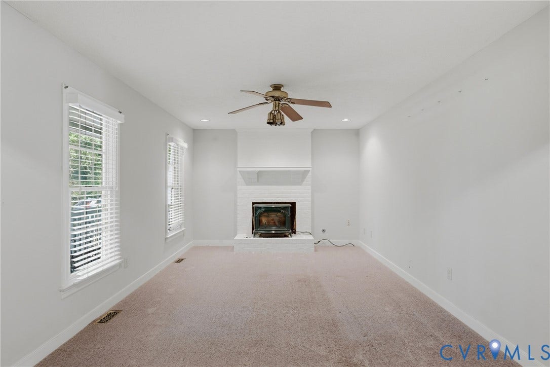 7270 Crossing Oaks Trail, Mechanicsville, VA 23111 Neutral-toned interior featuring a white-painted brick fireplace with a wood-burning insert, carpeting, recessed lighting, and a ceiling fan with integrated light fixtures