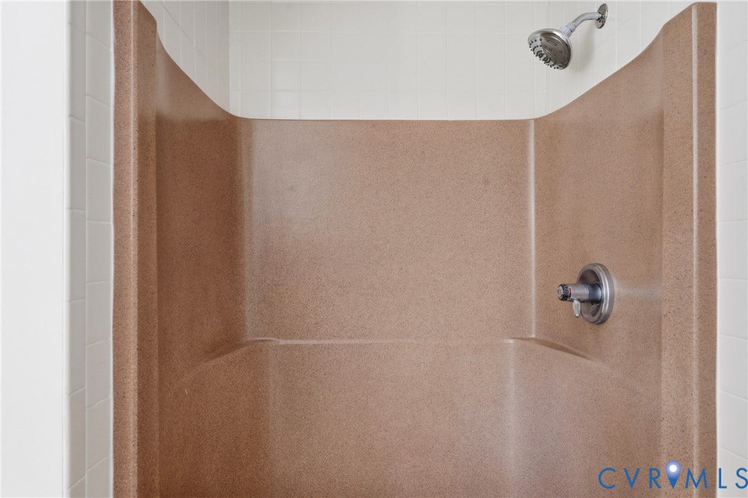 7270 Crossing Oaks Trail, Mechanicsville, VA 23111 Shower stall featuring a molded composite surround, white tile wall accents, and a brushed metallic shower head and mixing valve