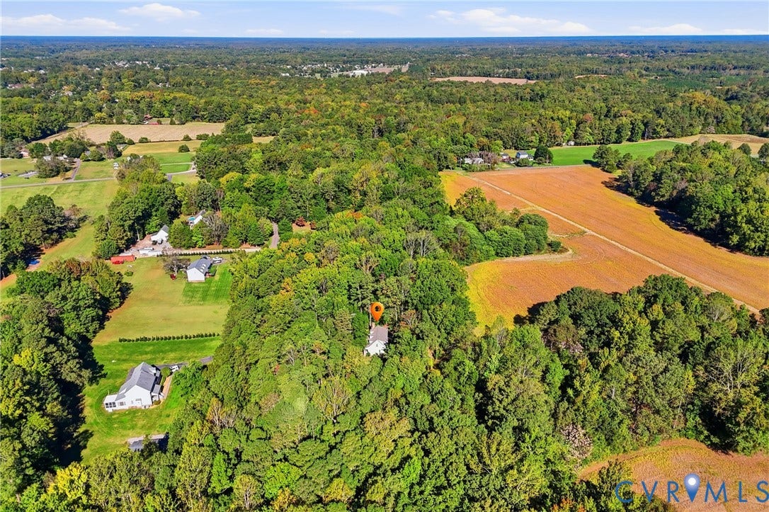 7270 Crossing Oaks Trail, Mechanicsville, VA 23111 Aerial perspective featuring a multi-story residence surrounded by dense woodland, mature trees, and expansive open fields