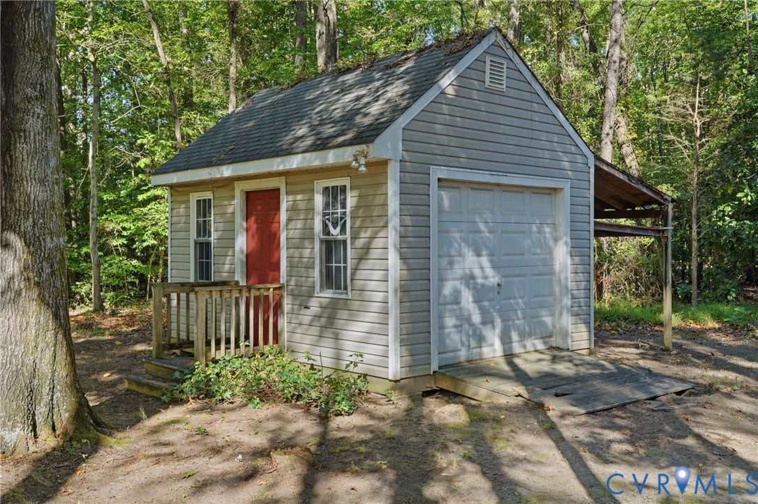 7270 Crossing Oaks Trail, Mechanicsville, VA 23111 Detached structure featuring light-colored horizontal siding, a gabled asphalt-shingled roof, a sectional garage door, a side-hinged entry door, and a covered lean-to area
