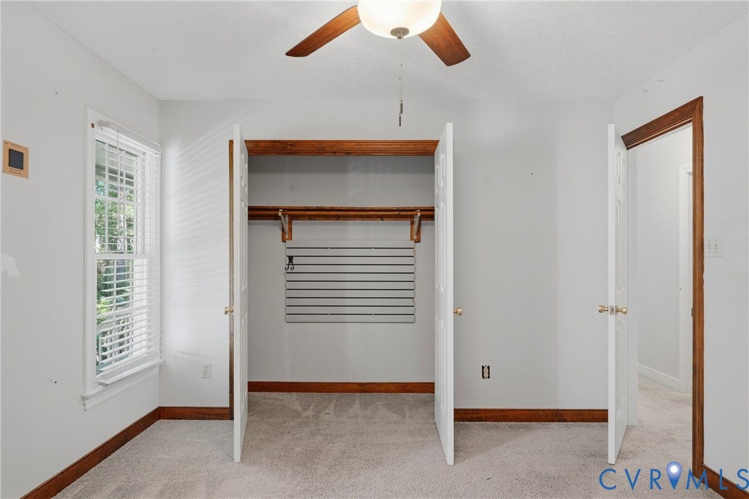7270 Crossing Oaks Trail, Mechanicsville, VA 23111 Carpeted room featuring a ceiling fan with integrated lighting, wood-trim windows, double-door closet with built-in shelving and slat wall organization, and solid wood door casings