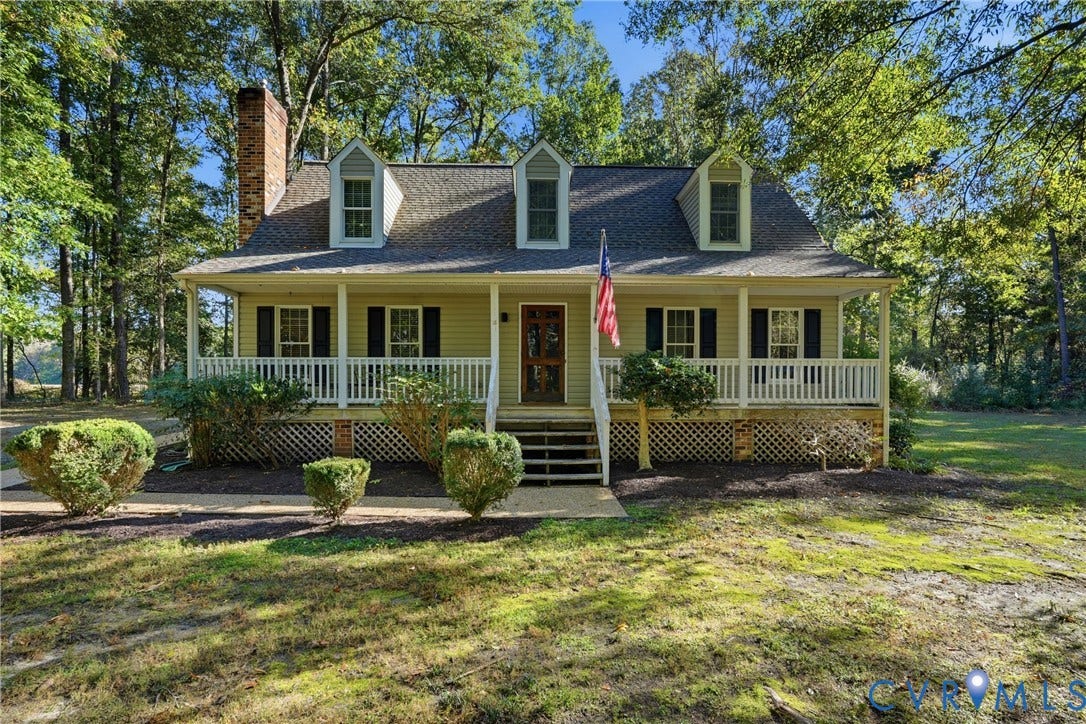 7270 Crossing Oaks Trail, Mechanicsville, VA 23111 Cape Cod-style residence featuring a full-width covered front porch, brick exterior chimney, three dormer windows, and white lattice skirting