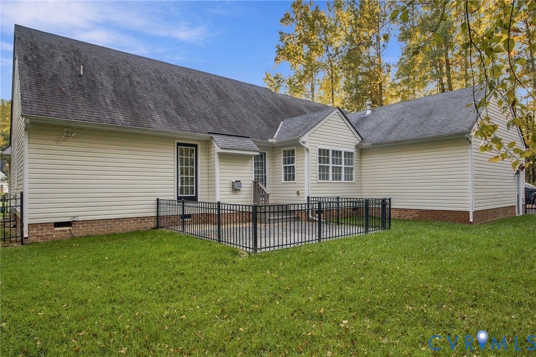 Vinyl siding exterior with a brick foundation, fenced concrete patio, and mature trees