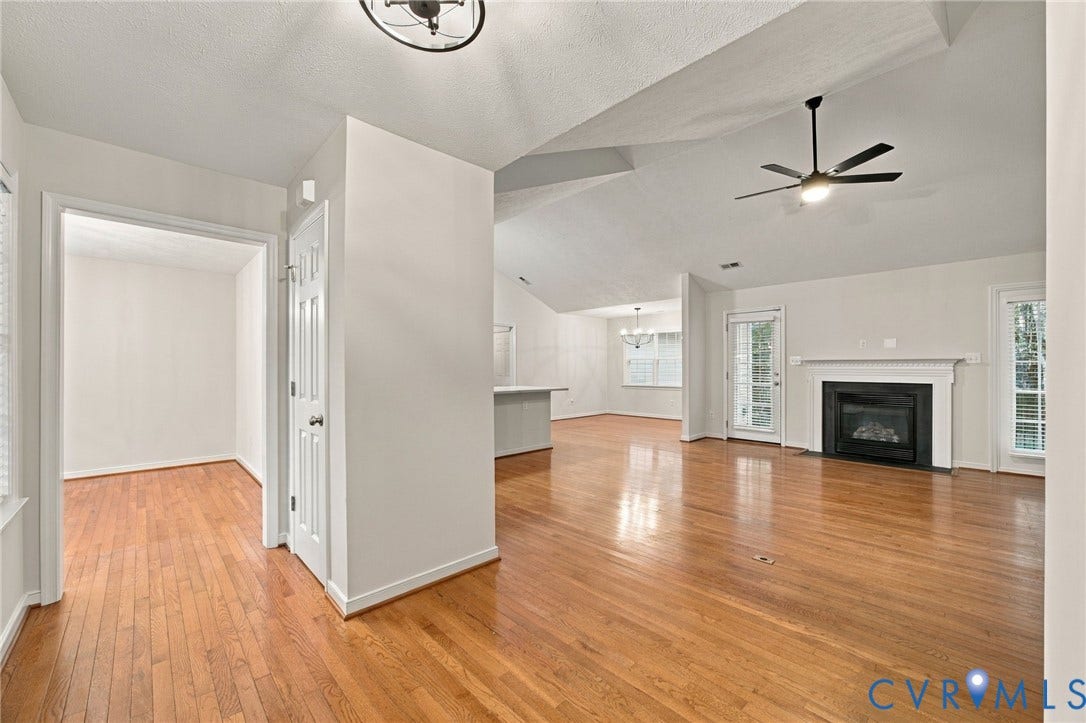 Vaulted ceilings, wood-finish flooring, built-in fireplace with mantle, ceiling fan, and multi-light chandelier